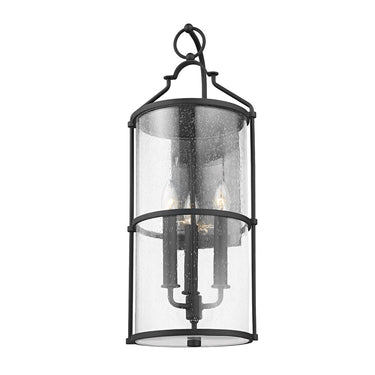 A black metal three-light wall sconce with clear seeded glass panels.